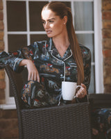 Seated model wearing The Hunt pyjama shirt, showing the horse and hound artwork and white collar piping.